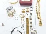 de nombreux bijoux posés sur une table blanche, à côté d'une boîte rouge