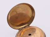 a gold pocket watch sitting on top of a white surface