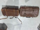 two brown leather bags sitting on a white surface