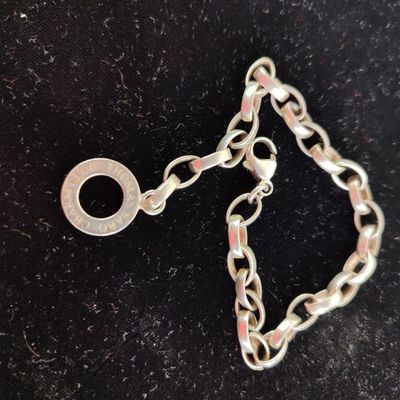 a close up of a silver chain bracelet on a black surface