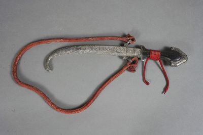 un petit objet métallique muni d'un cordon rouge