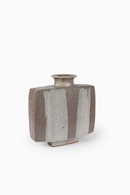 un vase brun et blanc posé sur une surface blanche