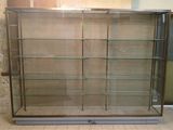 une vitrine avec des étagères en verre au milieu d'une pièce