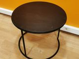 a small table with a black top on a wooden floor