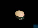 a white egg sitting on top of a black table