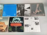 various albums of john lennon on display on a table