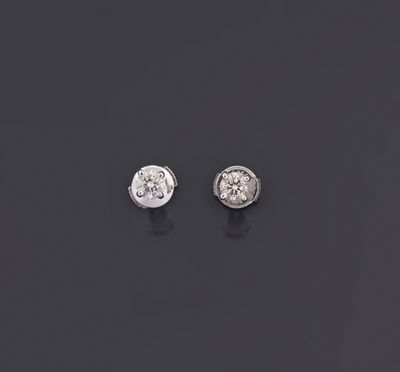 a pair of diamond earrings on a black surface