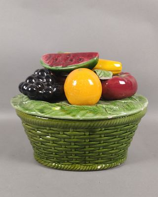 un panier vert rempli de fruits posé sur une table