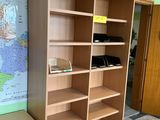 a wooden bookcase with a map on the wall behind it