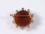 a close up of a gold broochle with a red stone in it