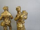 deux statues en bronze représentant des hommes debout l'un à côté de l'autre