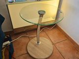 une table avec un plateau en verre et une bibliothèque remplie de livres