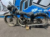 une vieille moto garée devant un mur recouvert de graffitis