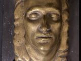 a gold sculpture of a woman ' s face on a black surface