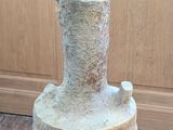 a stone vase sitting on a wooden floor next to a wall