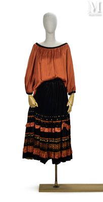 un mannequin portant une robe noire et orange, posé sur un socle