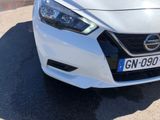 the front end of a white car parked on the side of the road