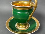 a green cup and saucer with a gold handle
