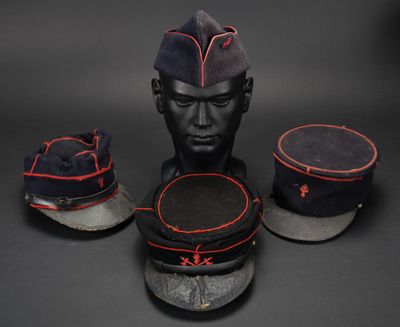 trois casquettes militaires et un porte-casquettes posés sur une surface noire