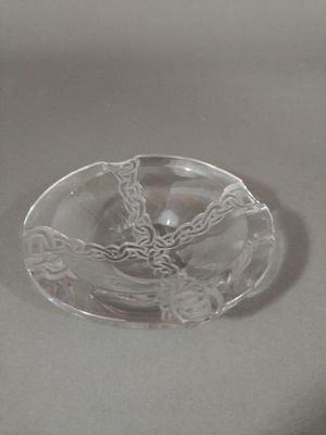 a clear glass ashtray with a decorative design on it