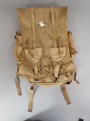 a tan backpack hanging on the wall next to a black chair