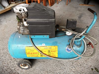 a blue air compressor sitting on the ground in the garage