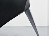 a black chair with a black seat and a white wall
