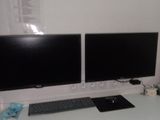 deux écrans d'ordinateur posés sur un bureau avec un clavier et une souris