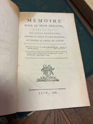 un livre ouvert posé sur une table en bois, à côté d'une pile de livres