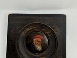 painting of a bearded man with a red hat and beard in a wooden frame