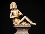 statue of a woman sitting on a pedestal holding a book