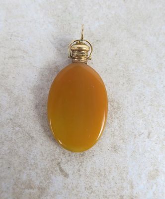 an orange agate pendant with a gold plated bail