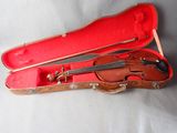 un violon dans un étui rouge posé sur une surface blanche
