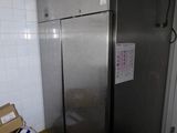 a silver refrigerator in the corner of a room with a box on the floor