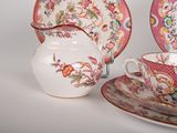 a tea pot and saucer sitting next to a cup and saucer