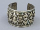 silver bracelet with flowers and birds on it on a gray surface