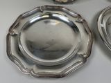 three silver plates sitting on a table next to each other