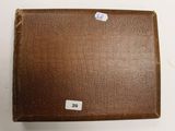une valise marron avec une étiquette, posée sur une table