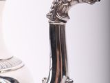 a silver tea pot with a dragon head on it