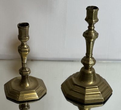 pair of antique brass candlesticks on a glass table