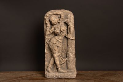 une statue en pierre représentant un homme tenant une épée, posée sur une table en bois