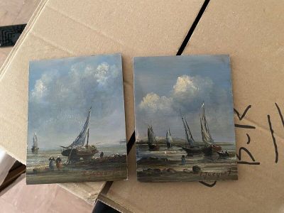 two paintings of boats are on a cardboard box on a table