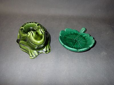 a green frog sitting on a leaf shaped dish