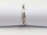 bracelet à chaîne en argent posé sur une serviette, sur fond blanc