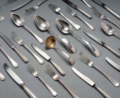 un grand nombre de cuillères et de fourchettes disposées sur la table