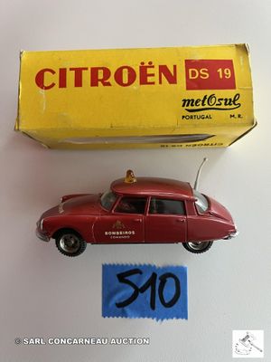 une petite voiture rouge posée sur une table à côté d'une boîte jaune