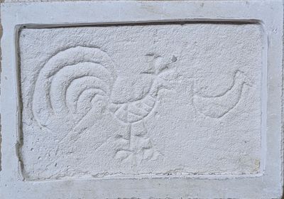 un bloc de pierre sur lequel sont sculptés un coq et un oiseau