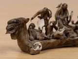 figurines of a group of monkeys sitting on top of a piece of wood