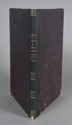 an old book with a black cover sitting on top of a table