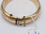 a close up of a gold bracelet with a tag on it